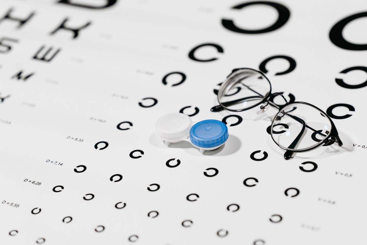 Home Close-up of contact lens case and eyeglasses on an eye test chart, ideal for vision care concepts.